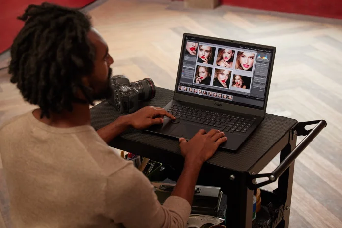 A man using a ProArt Studiobook Pro 16 OLED laptop on a photography cart to edit photos on-set