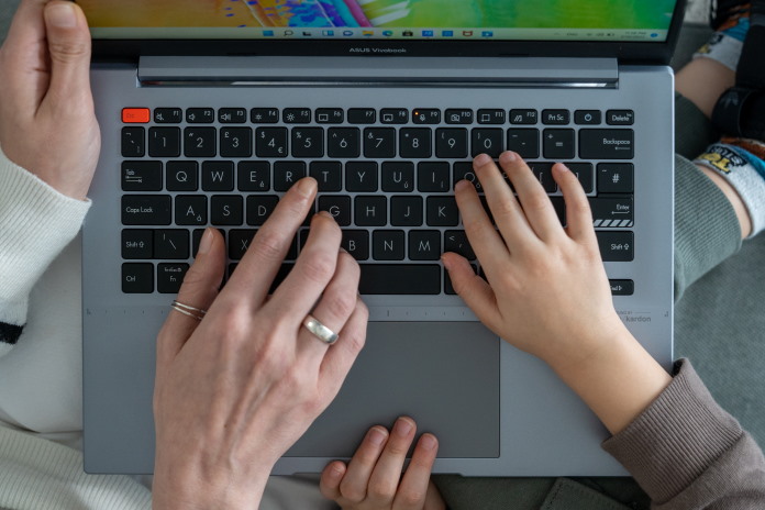 A family's hands on top of a laptop keyboard