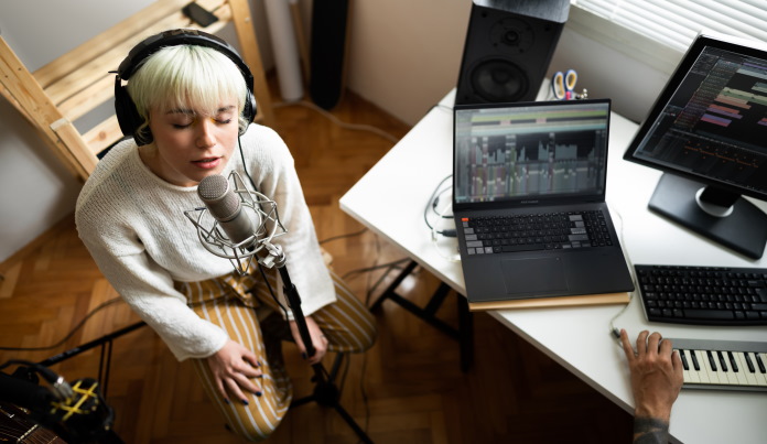 Woman recording music using a laptop