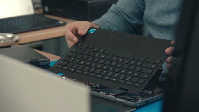 IT staff removing a keyboard deck from a laptop to service the device