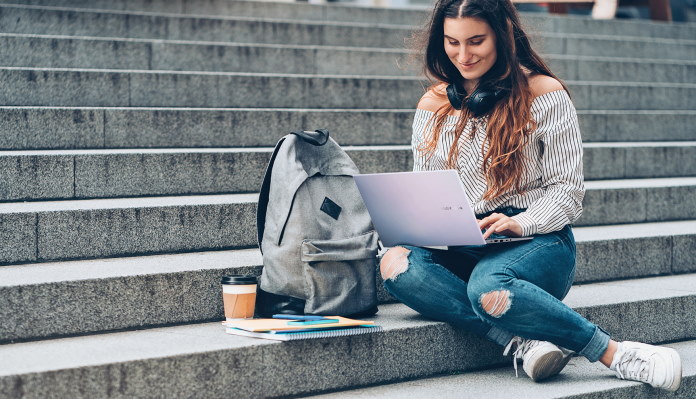 Woman sitting on steps with her backpack, using Vivobook S15 laptop