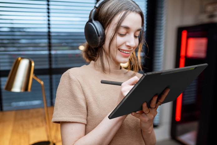 Young woman listening to music and working with a stylus on her Vivobook 13 Slate OLED