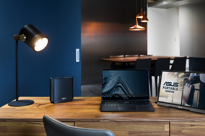 ASUS router, laptop, and portable monitor at a home office desk