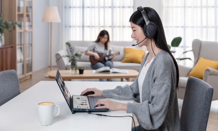 Two women working on separate devices in the same room