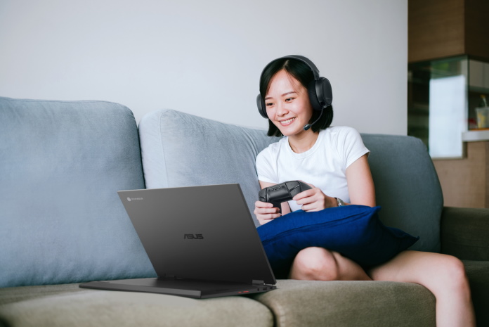 Woman sitting on a couch using a controller to play a game on her Chromebook in stand mode 