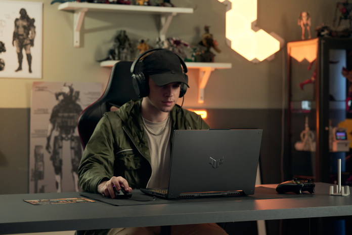Gamer running through a colorful background holding an ROG laptop