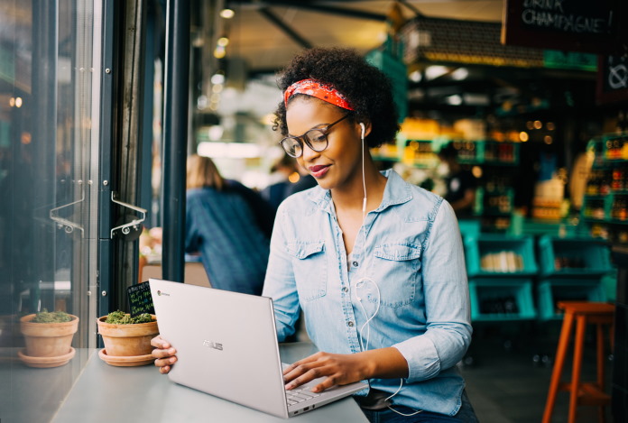 Woman at a coffee shop using a Chromebook on a window counter 