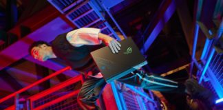 Gamer running through a colorful background holding an ROG laptop