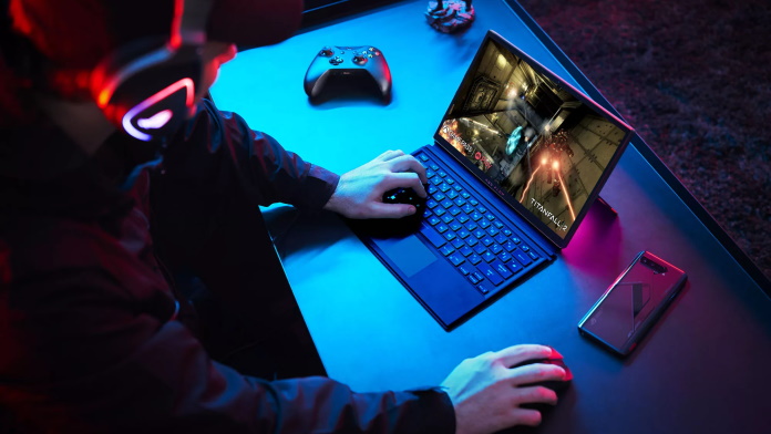 Young man playing games with the ROG Flow Z13 with a controller and smartphone nearby