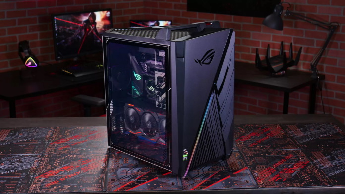 ROG Strix GA35 gaming desktop PC on a table with full gaming setup in the background