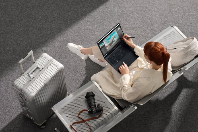 A woman using a stylus to create digital art in an airport using the Zenbook Pro 14 OLED