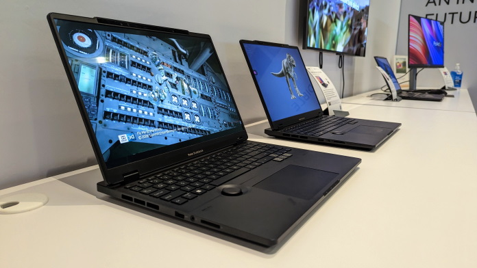 ProArt Studiobook 16 3D OLED laptops lineup on a table with the ProArt Display PA279CRV in the background