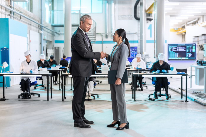 Man and woman shaking hands in a sustainability research facility 