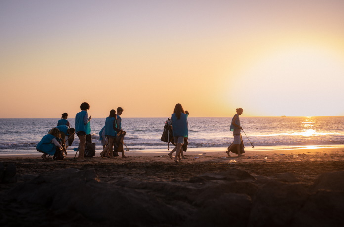 A group of people on the beach picking up litter together