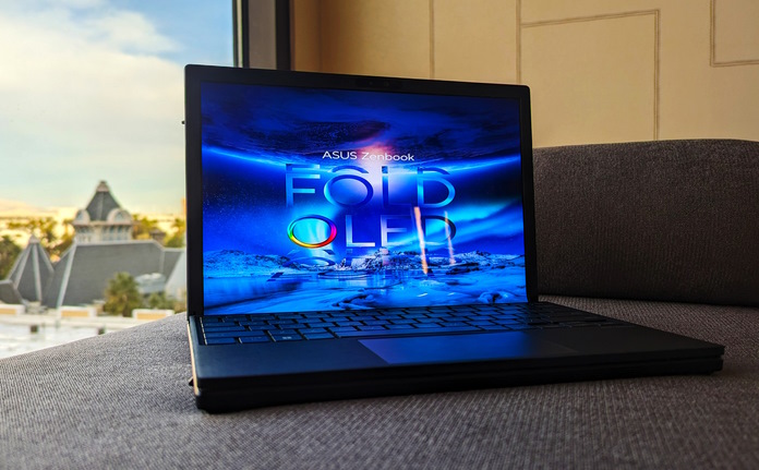 Zenbook 17 Fold OLED laptop in clamshell mode on sitting couch with a city skyline in the background