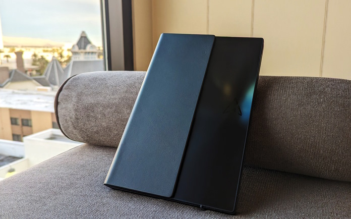 The Zenbook 17 Fold OLED closed and leaning on the arm of a couch