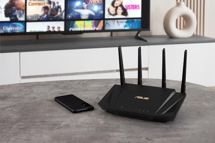 An ASUS extendable router and smartphone in a living room with a smart TV in the background