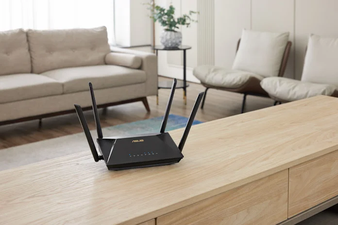 An ASUS extendable router on a low table in a living room with couch and chairs behind