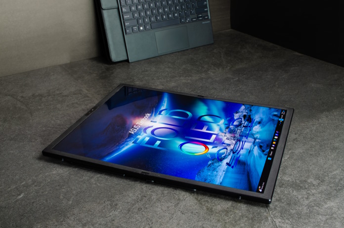 Zenbook 17 Fold OLED in tablet mode, laid flat on a surface with its keyboard and leather carrying case in the background