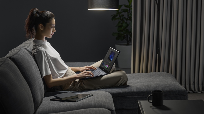 Woman sitting on a couch using the Zenbook Pro 17 laptop 