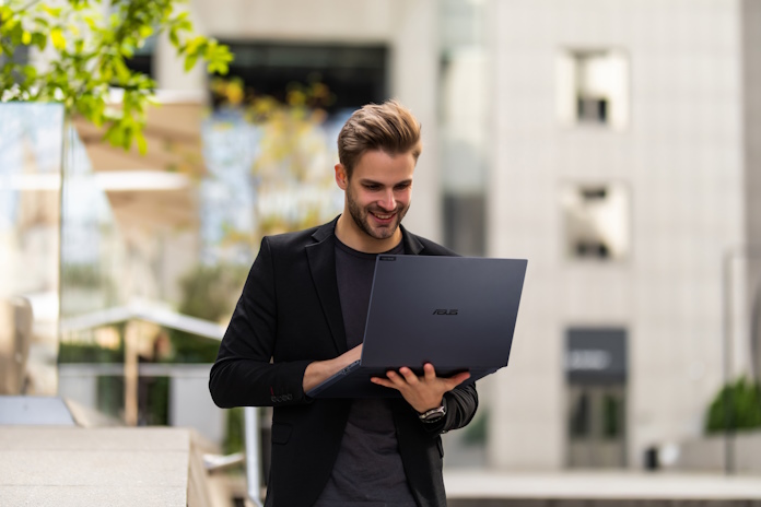 Businessman walking down a street holding his ASUS ExpertBook laptop