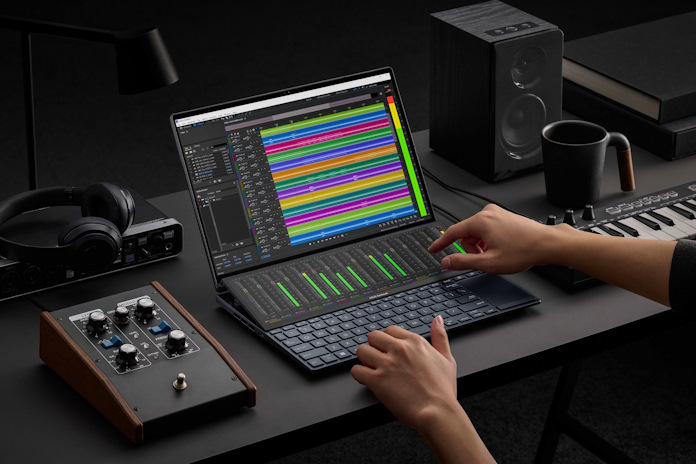 Musician using the Zenbook Pro 14 Duo OLED to mix music on a table with other audio gear