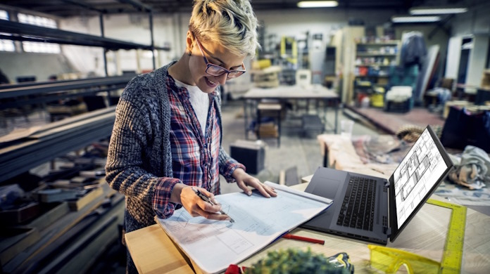 A woman working in an industrial setting with an ExpertBook laptop