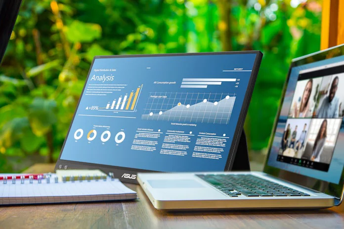 The ZenScreen MB16ACV portable monitor on a table with an ASUS laptop and a notebook