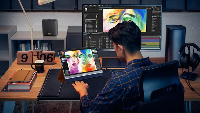 A young man doing photo editing with a portable display and a large desktop monitor