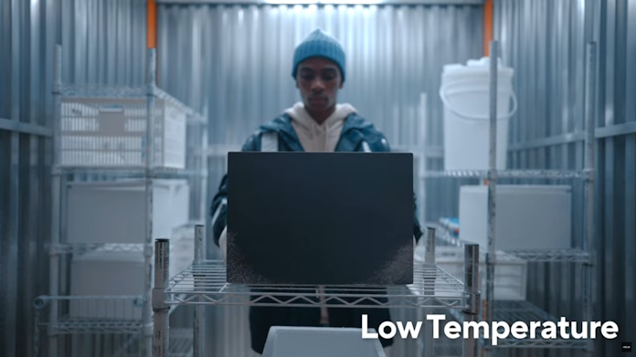 A man using a laptop in the low temperature environment of a freezer