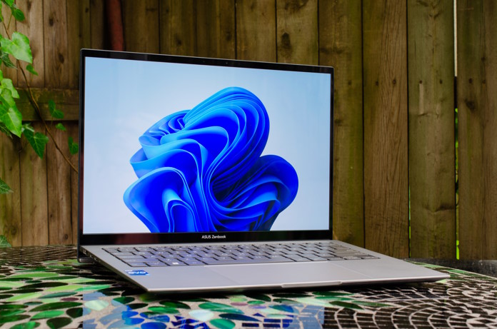 The Zenbook S 13 OLED laptop on a stone table in front of a wooden fence