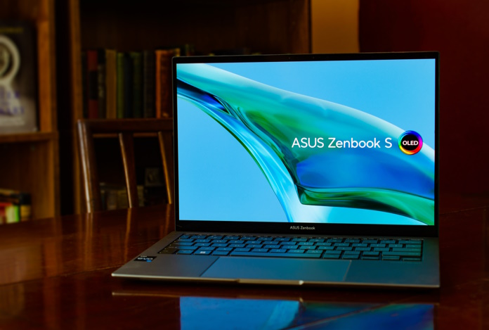 Zenbook S 13 OLED laptop sitting open on an antique wooden table with bookshelves in the background