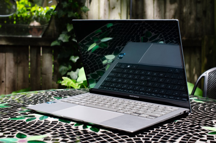 Zenbook S 13 OLED laptop sitting open on a stone table in a backyard 