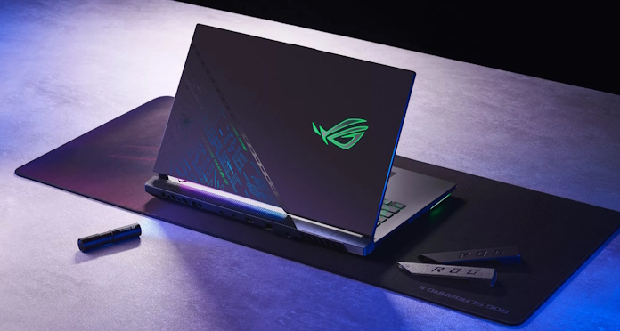 The ROG Strix SCAR 17 SE gaming laptop on a table with a mousepad and a special light showing the hidden cipher on the lid