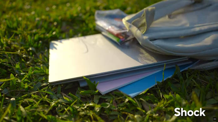 A laptop undergoing the shock of being carelessly dropped on the ground from an open backpack 