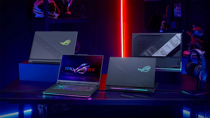 An array of ROG Strix G laptops laid out on a table with ROG gear in the background