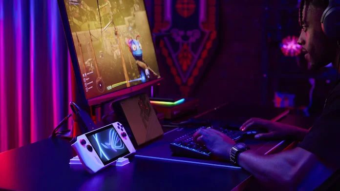 The ROG XG Mobile external GPU and docking station connected to the ROG Ally and peripherals, with a young man using the full setup to game
