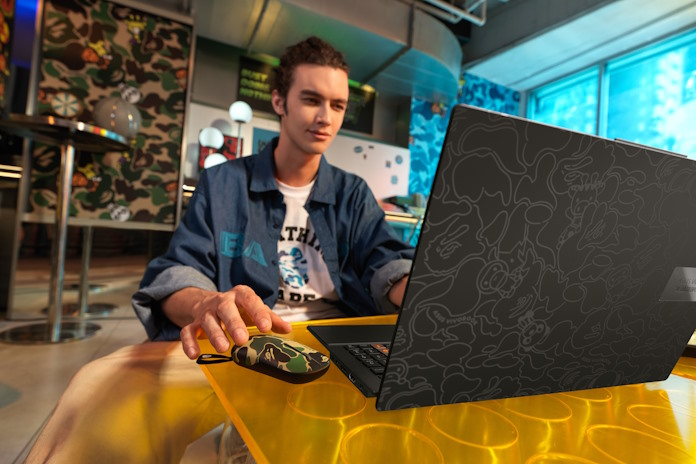 A young man reaching out for his mouse as he works on his laptop 