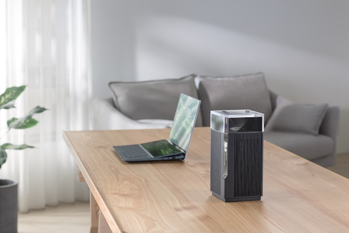 A ZenWiFi node on a table with an ASUS laptop and smartphone in the background