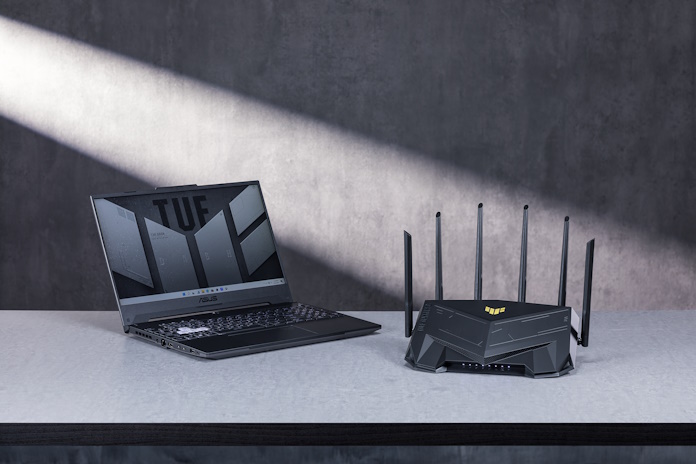 The TUF Gaming AX6000 wireless router on a table with the TUF Gaming A15 laptop