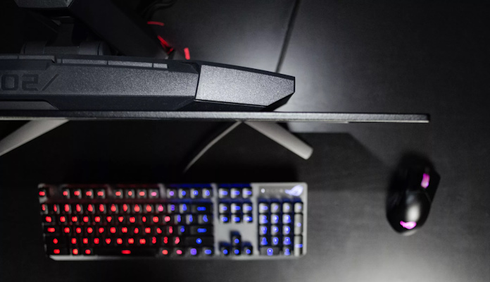 A top down view of the ROG Swift OLED PG27AQDM gaming monitor showing an ROG keyboard and mouse 