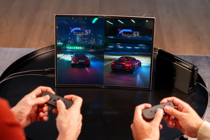 Two people playing a racing game on the Nintendo Switch together using a portable display
