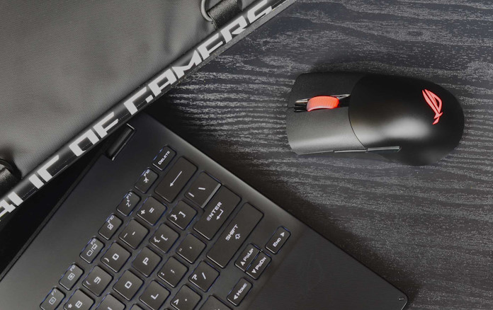 The ROG Keris Wireless gaming mouse on a desk next to an ROG laptop