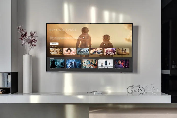 A large-screen TV on a wall in a living space with an ASUS NUC beneath it driving the media experience