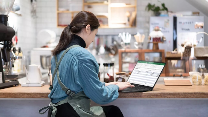 A business owner working on a spreadsheet in a cafe