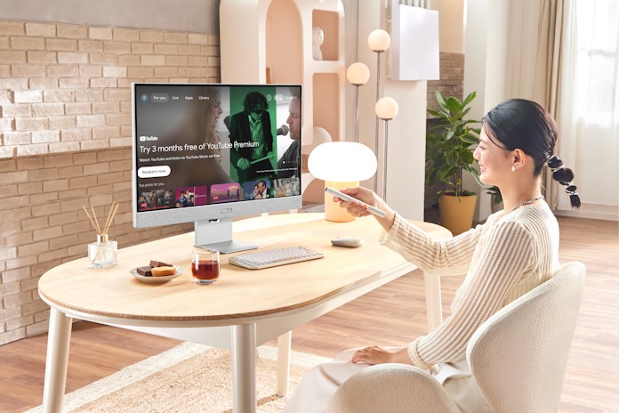 A young woman adjusts the content on her smart monitor using a remote control 