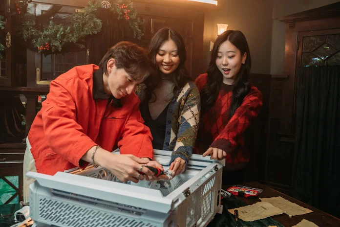 Three friends build a PC together in a festive room