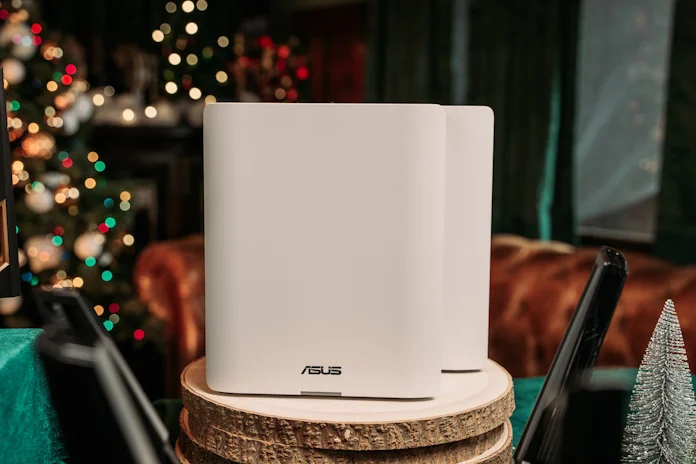 An ASUS ZenWiFi BT10 mesh router on a table in a festive room