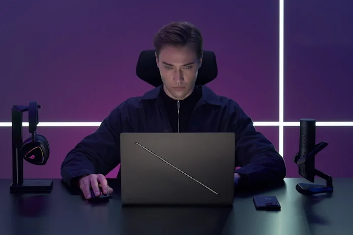 A young man games with an ROG Zephyrus G16 gaming laptop