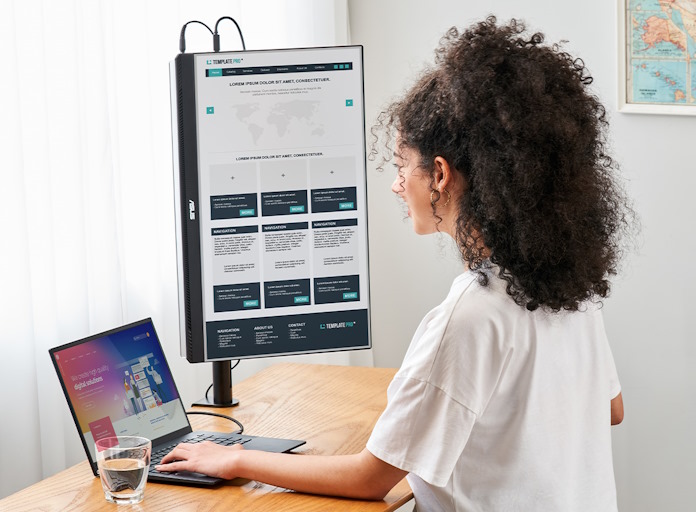 A young woman works at her laptop with the ZenScreen MB27ACF in a vertical orientation